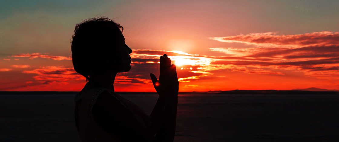 woman practicing yoga as the sun sets