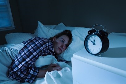 woman suffering from insomnia looking at her alarm clock