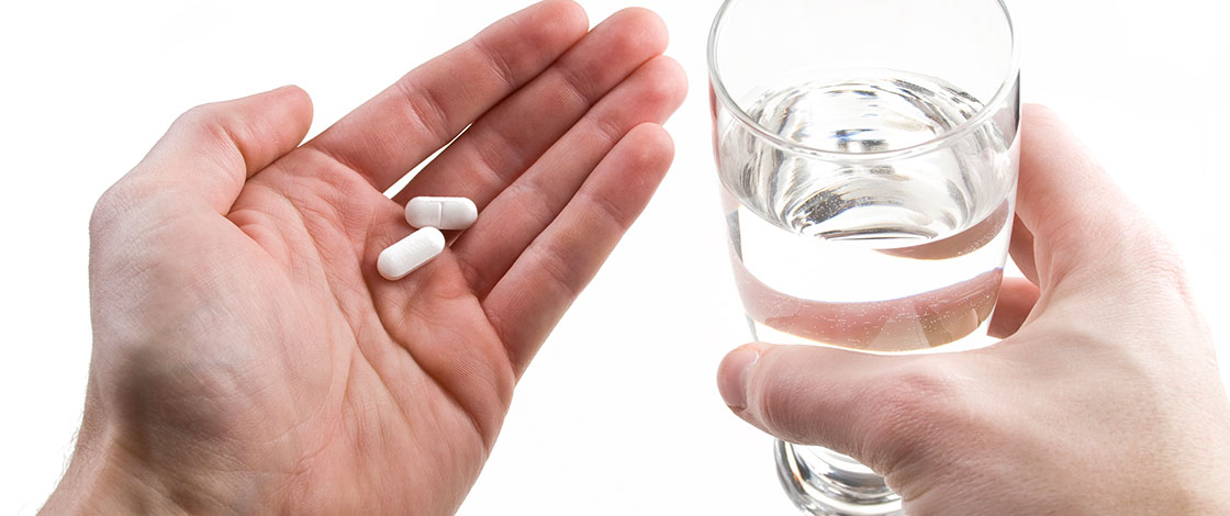 person talking pills with a glass of water