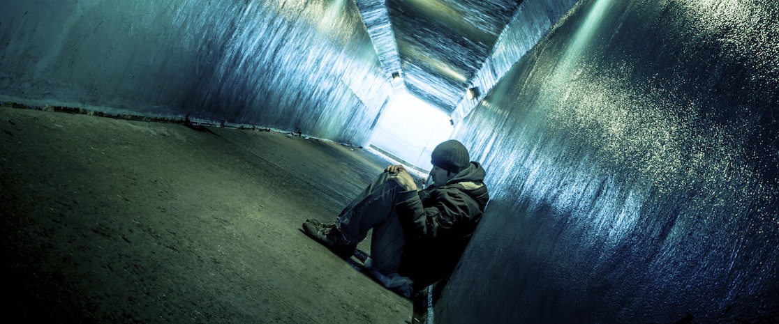 man sitting in a dark tunnel