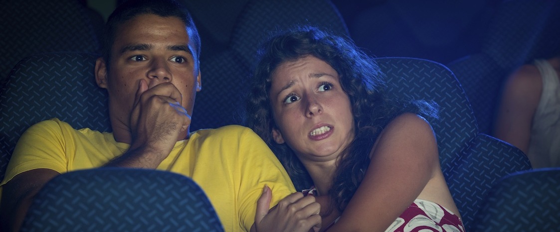 Scared couple watching movie in cinema