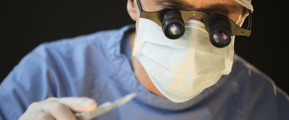 Surgeon Wearing Mask And Magnifying Glasses Holding Scalpel