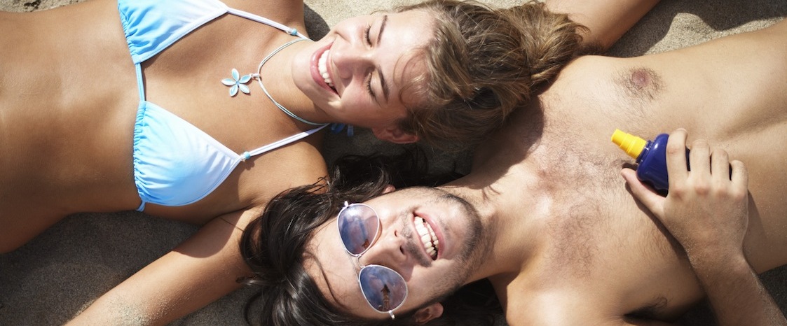 Couple lying on beach, smiling, overhead view