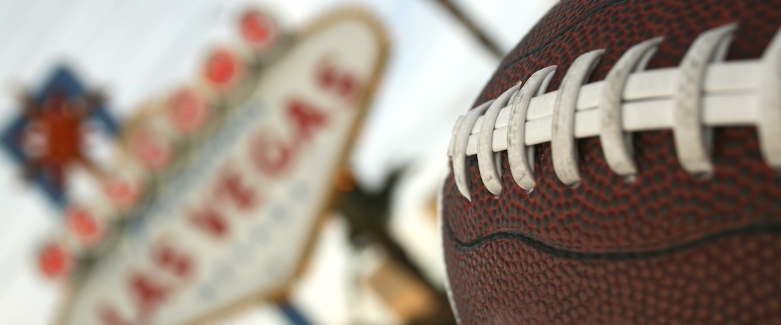 close-up of a football with Vegas sign in the background