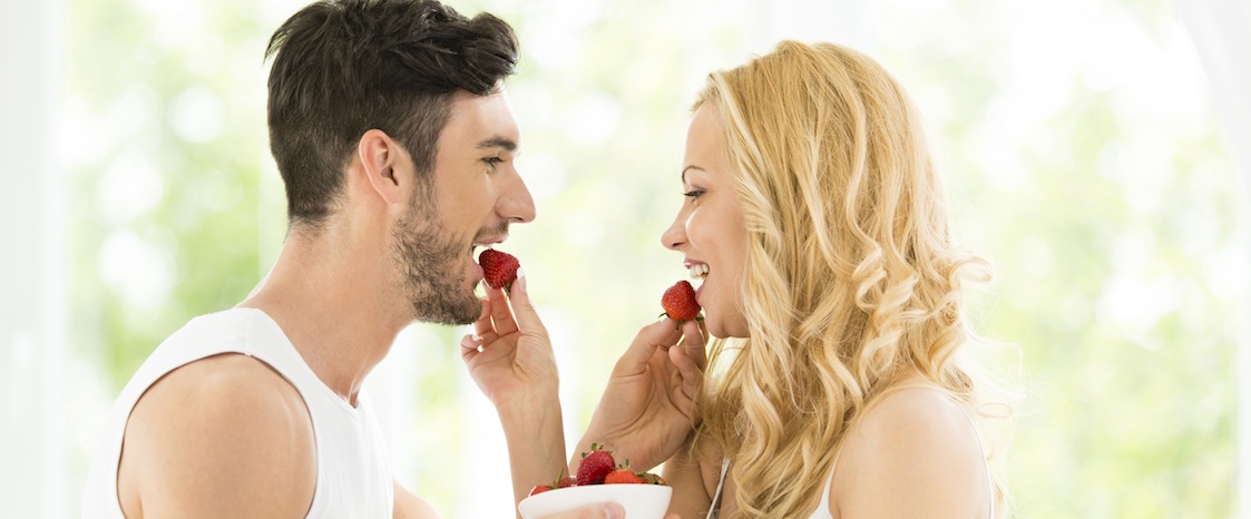 Woman and man in love eating strawberries.