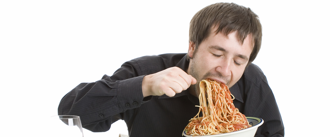 man binge eating spaghetti