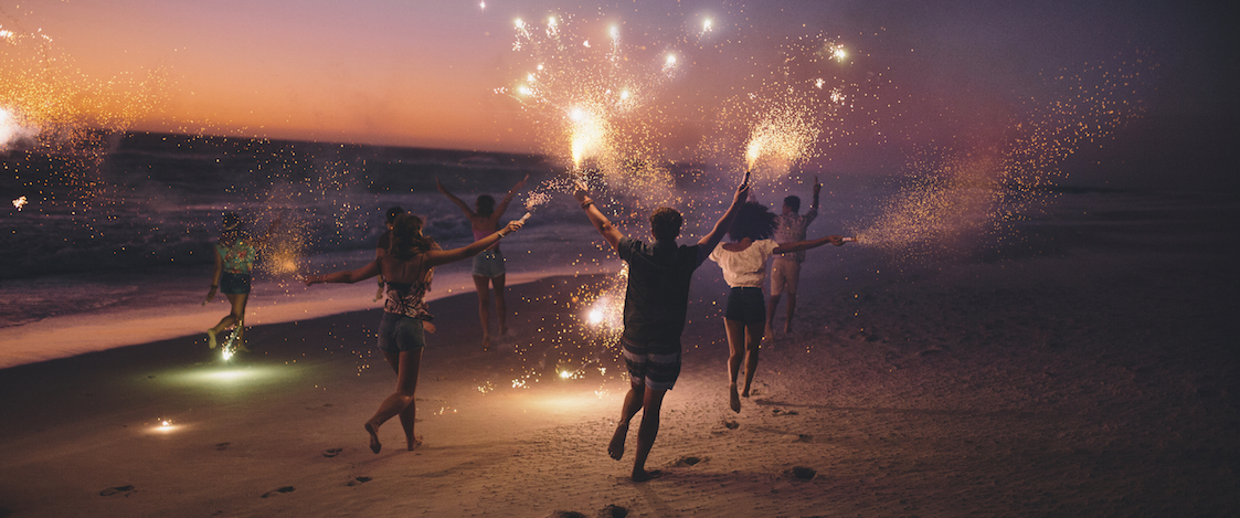 people celebrating on beach with sparklers