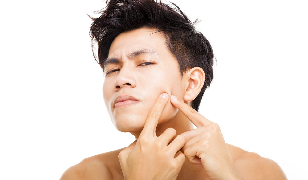 guy picking at pimple on his face
