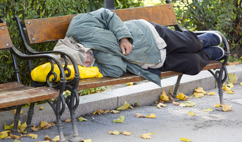 homeless man sleeping on park bench