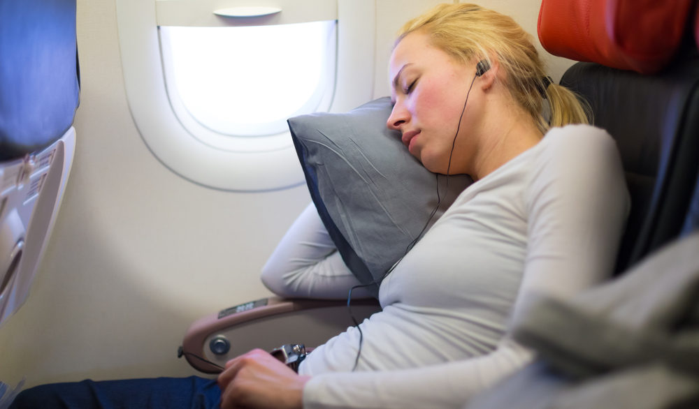 blonde woman sleeping on pillow in airplane